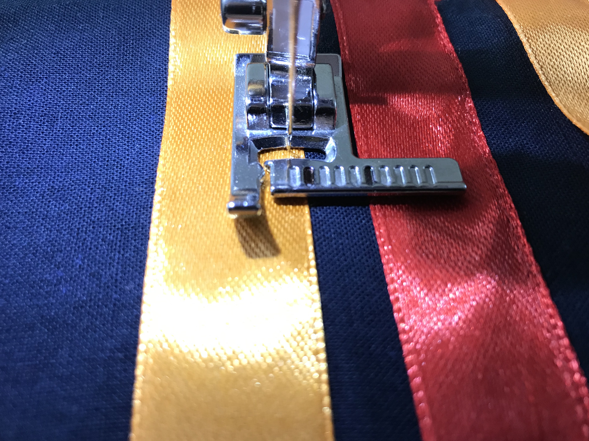 Sewing a ribbon to fabric using presser foot with a ruler.