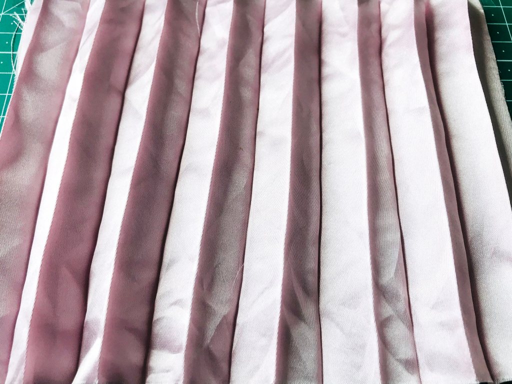 Creased permanently pleated satin fabric. Permanent accordion pleats.
