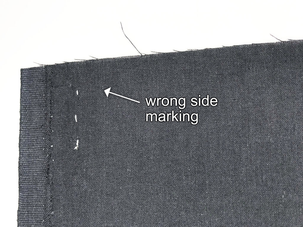 Marking the wrong side of a fabric along the selvage line with basting thread.