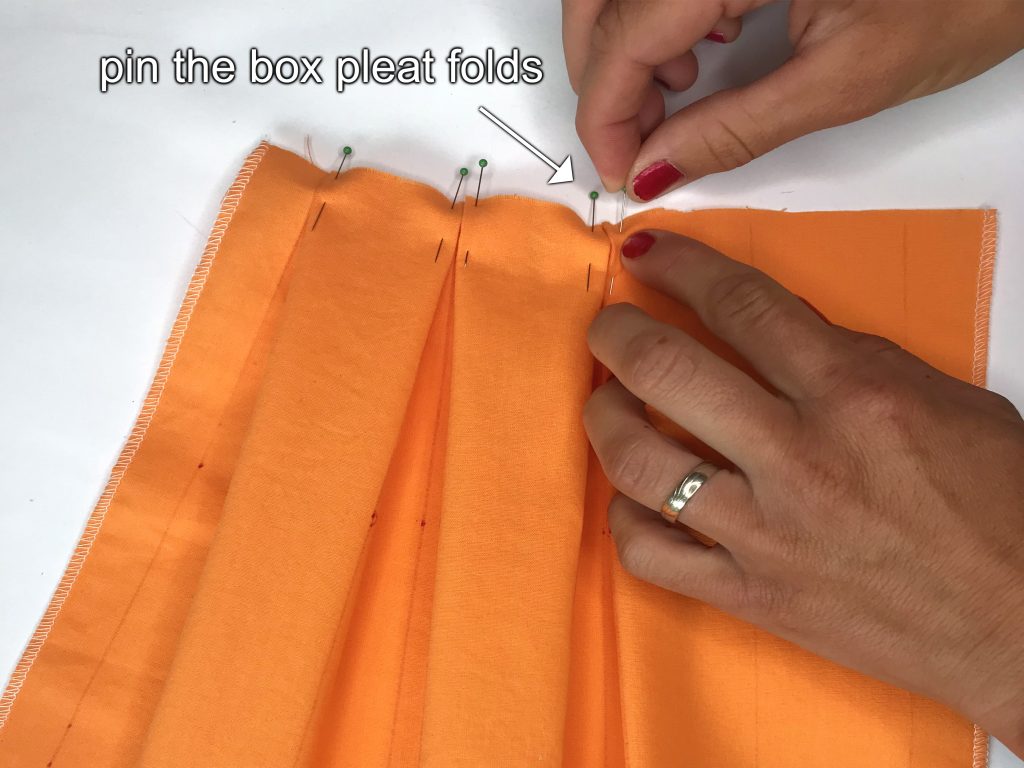 Pinning box pleats to hold them in place.