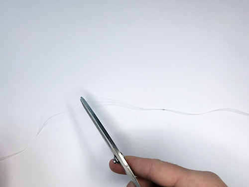 Cutting away excess string with scissors.