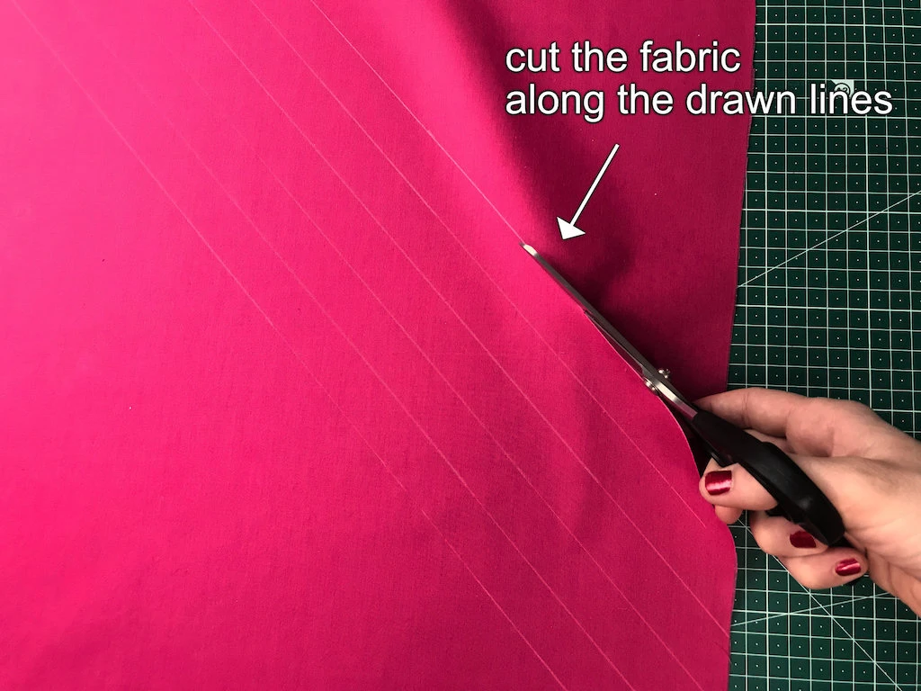 Cutting the fabric on the bias along pre-drawn lines.