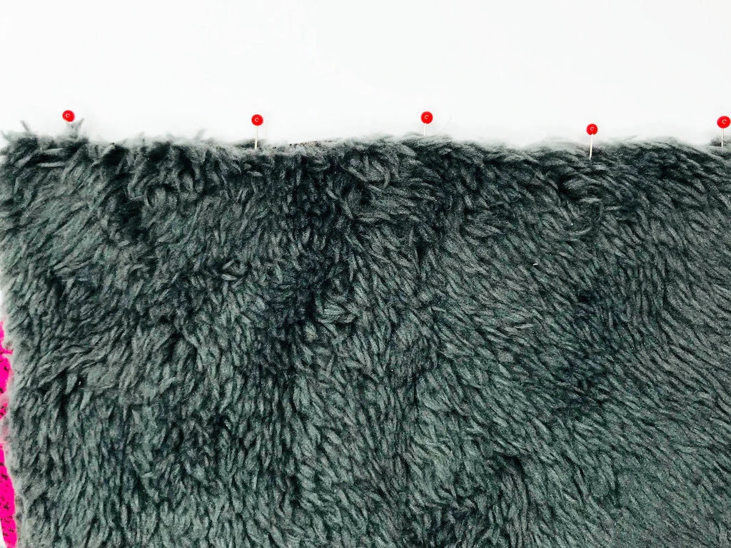 Furry fabric pinned together. Pins perpendicular to fabric edge.