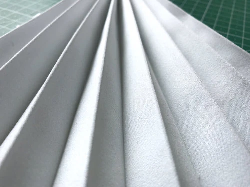 Permanently pleated duchess satin fabric. Permanent accordion pleats.
