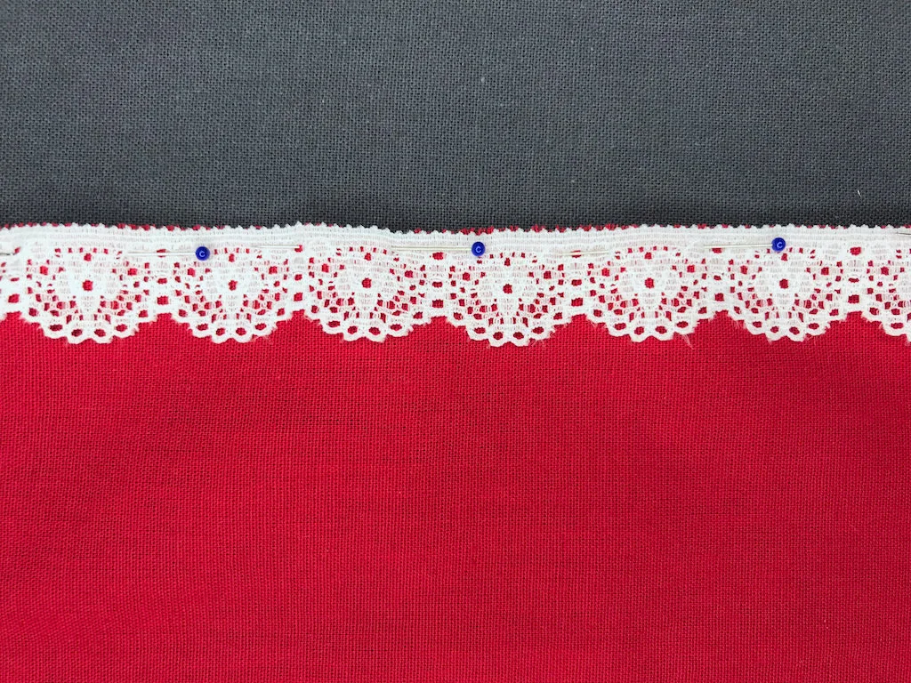 Lace trim pinned to fabric edge.