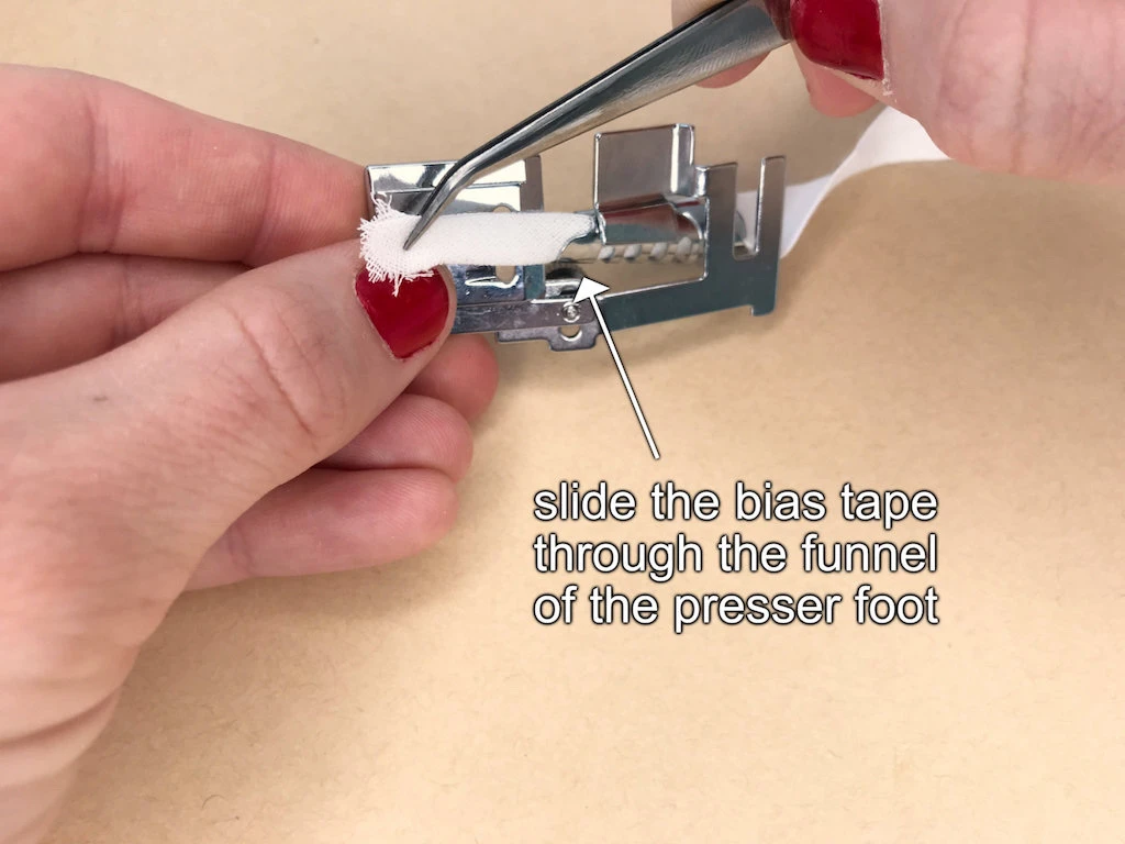 Sliding a tape through the funnel of the presser foot for sewing bias tapes.