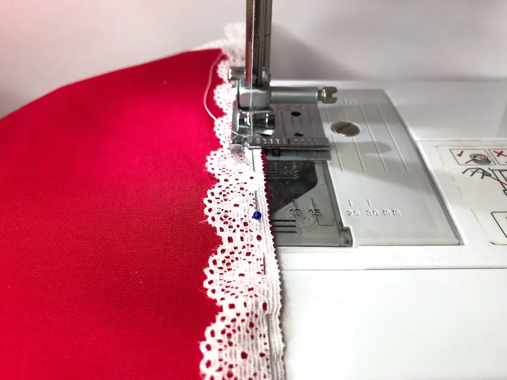 Sewing a lace trim to cotton fabric with a zigzag stitch.