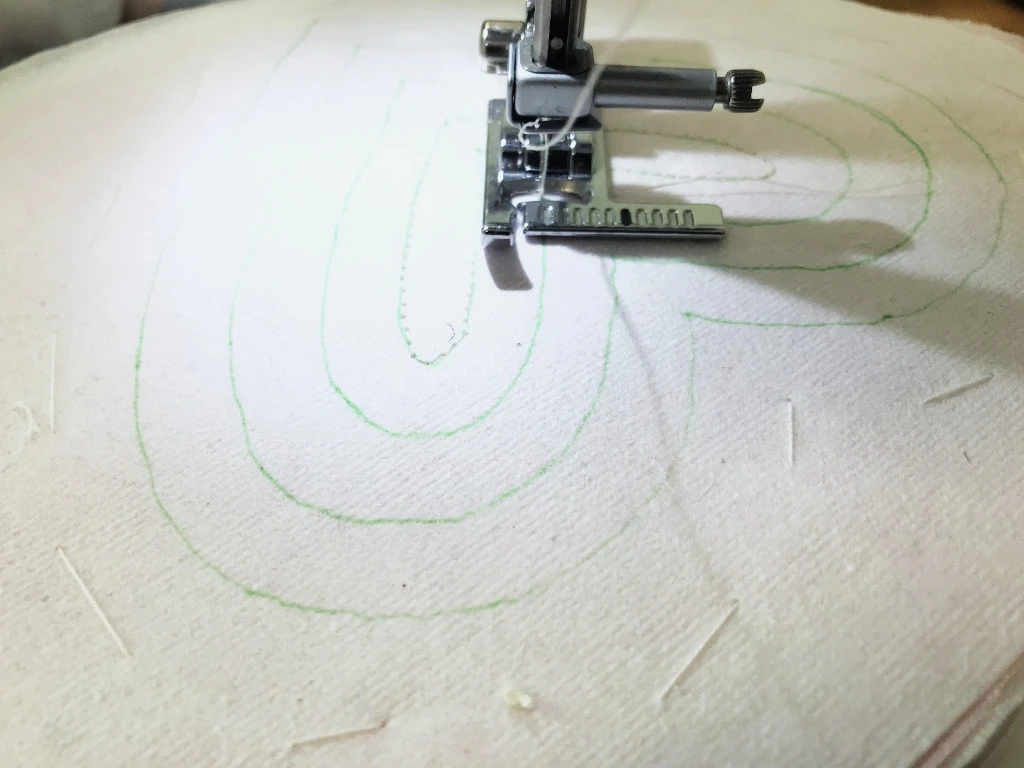 Sewing stitches according to heart template on a stabiliser.