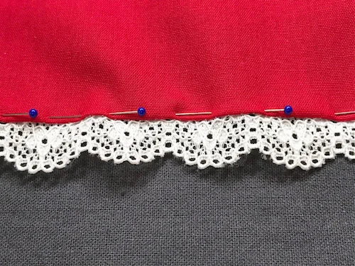 Right side of lace trim pinned to fabric.