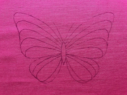 Butterfly template and cotton fabric placed on a tracing pad.