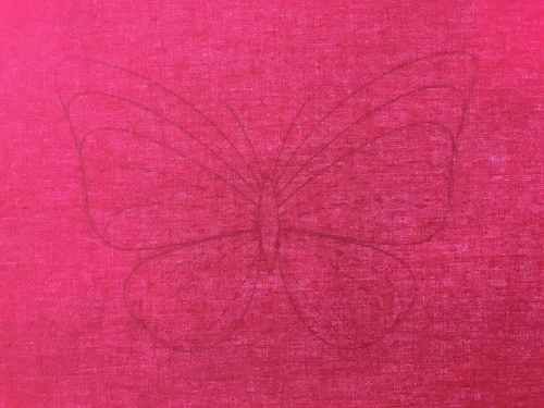 Butterfly template and cotton fabric placed on a tracing pad.