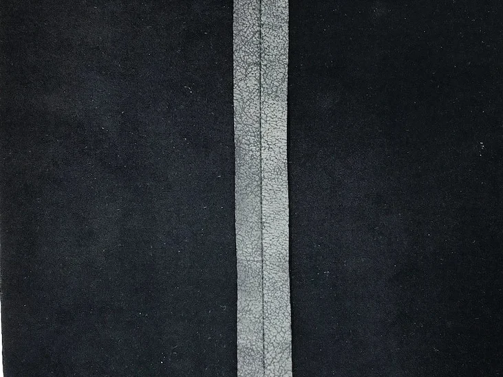 Unfinished raw edges of leather imitation knit fabric.