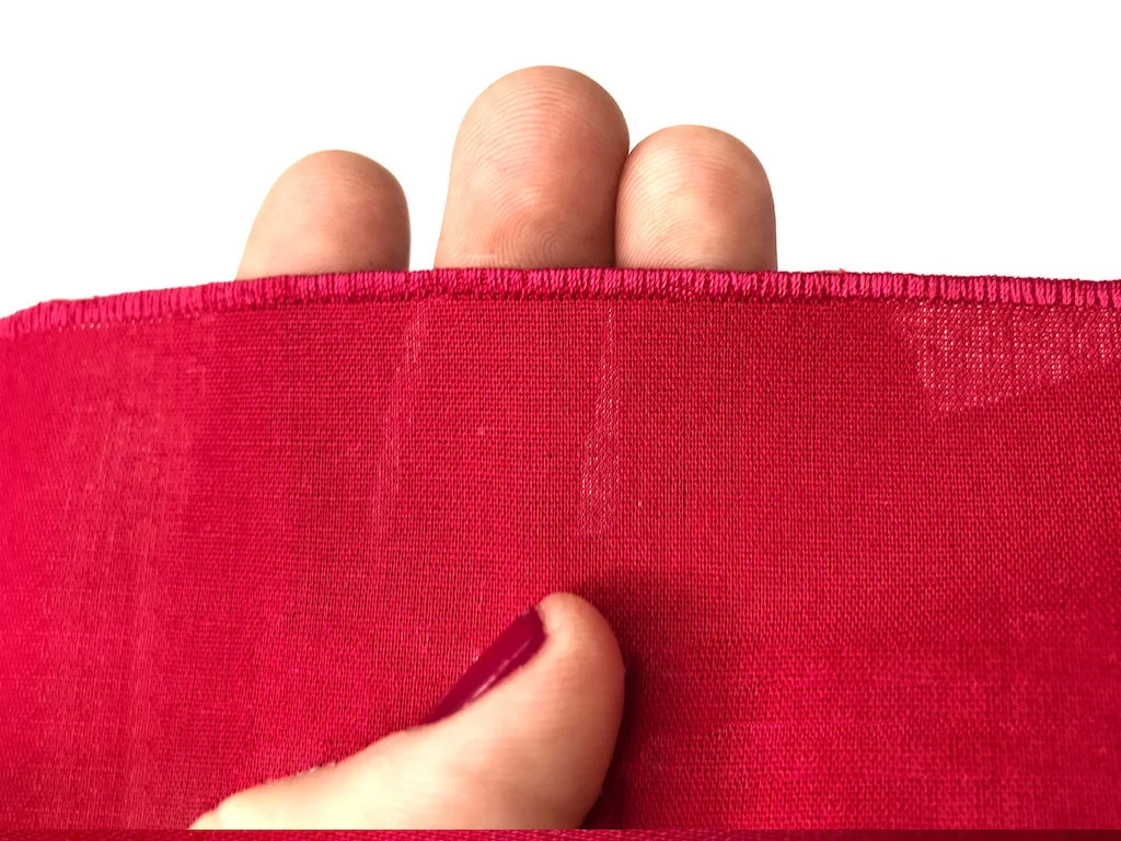 Dense zig-zag stitch used as hem finis on a piece of cotton fabric.