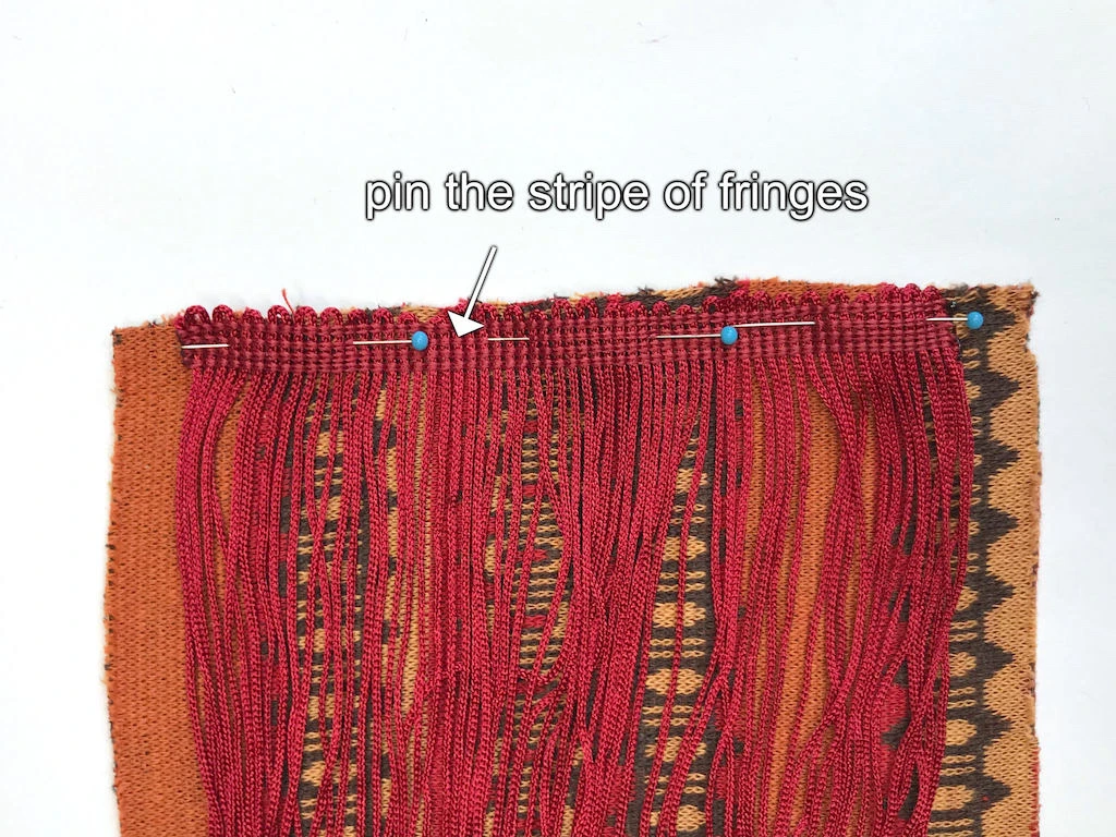 Stripe of fringes pinned to a shorter side of a fabric recgangle.