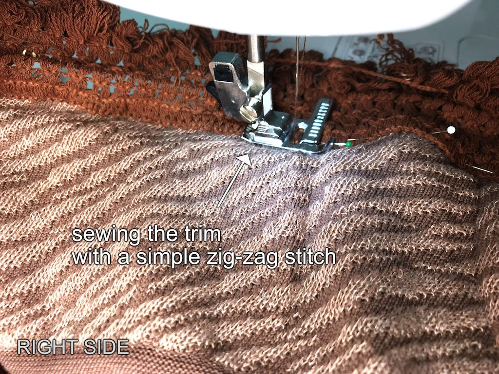 Sewing a fringe trim to the sweater hem using a simple zig-zag stitch.