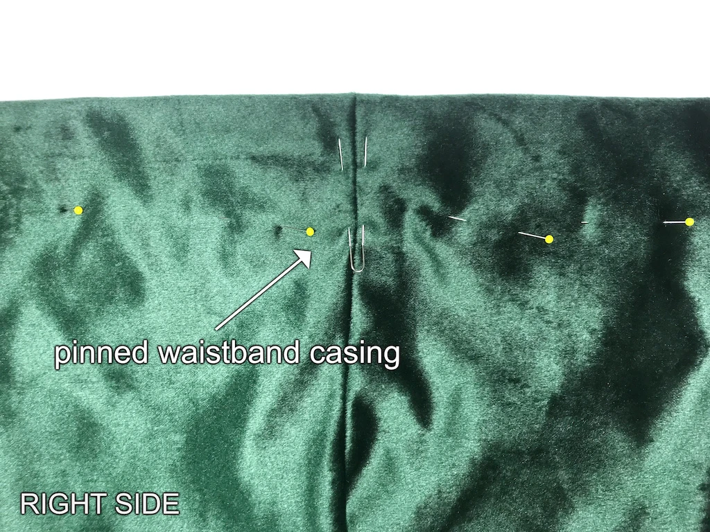 Folded and pinned fabric making an elastic waistband casing.