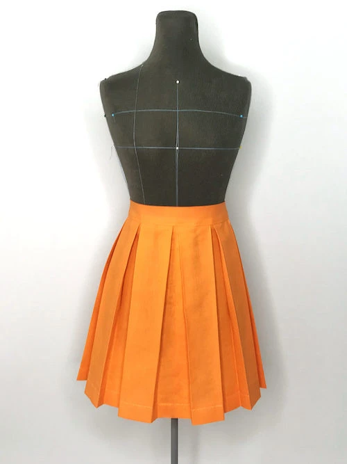 Orange pleated skirt with box pleats.